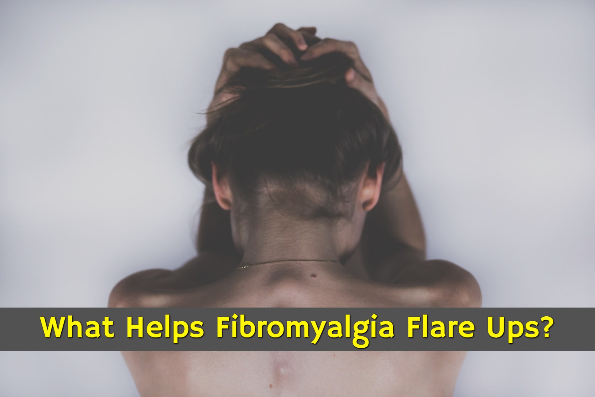 Woman in pain, holding her head experiencing fibromyalgia flare ups